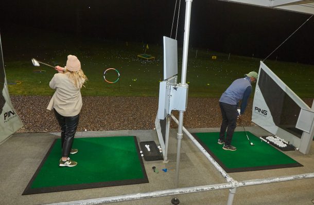 People practicing golf shots at a golf range
