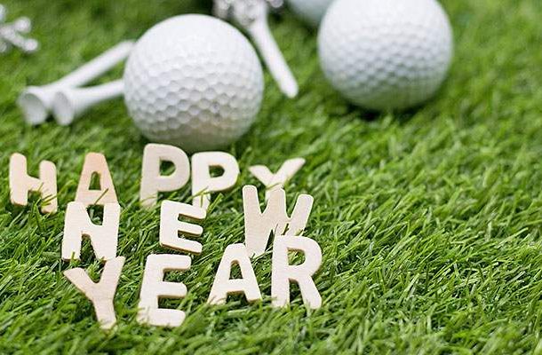 Field with golf balls and happy new year sign on the grass