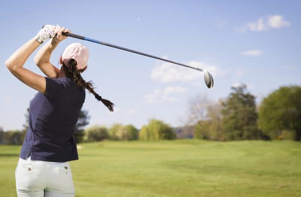 Woman golf player teeing off.